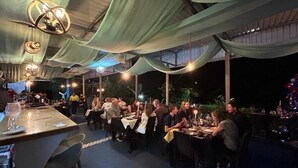An outdoor dining area with tables and chairs under a covered structure with draped fabric. - Ecolodge Kala Luna Resort (Drake Bay)