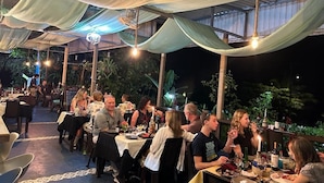 An outdoor dining area with tables and chairs under a covered roof, surrounded by greenery. - Ecolodge Kala Luna Resort (Drake Bay)