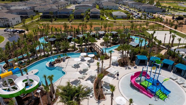 A resort with a large pool area, multiple water slides, and lounge chairs. - Windsor Cay 5BR Villa | Private Pool & Game Loft (Clermont)