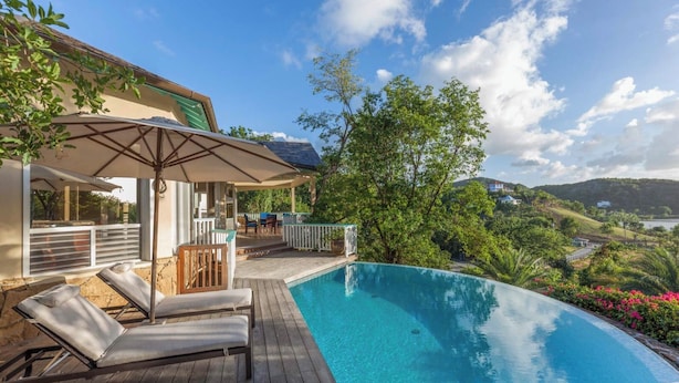 A poolside area with lounge chairs and a pergola, overlooking a scenic landscape. - Villa Tramonto. Great view, pool, exclusive area and beach at walking distance. (St. Johns)