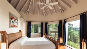 A spacious bedroom with a large bed, wooden headboard, and a ceiling fan. - Villa Tramonto. Great view, pool, exclusive area and beach at walking distance. (St. Johns)