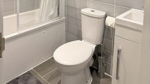 Une salle de bain avec douche, toilettes et lavabo.