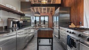 A modern kitchen with stainless steel appliances, wooden accents, and large windows offering a view.
