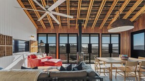 A modern living room with a ceiling fan, large windows, a red sofa, and a dining area.