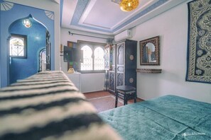 A room with a bed, a window with a view, a wardrobe, and a wall with a decorative mirror. - Dar Rafik (Chefchaouen)