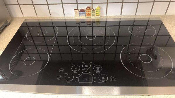 A black induction cooktop with a control panel and a tiled backsplash.