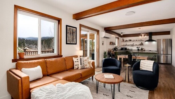 A modern living room with a sofa, chairs, a coffee table, and a view of the outdoors. - Aspen Glow Cabin - a charming 2-bedroom cabin with mountain views & wood stove (Bailey)