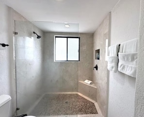 A modern bathroom with a glass shower enclosure, a built-in bench, and a towel rack. - 2BD Beach Front Luxury in Cabo (San José del Cabo)