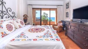 Une chambre à coucher avec un lit, une télévision, une commode et une vue sur l’océan.