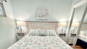 Ein Schlafzimmer mit einem Bett, Nachttischen, einem Spiegel und einem Wandbild.