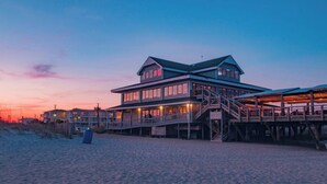 Ein mehrstöckiges Hotel direkt am Strand, mit Balkon und überdachtem Gang.