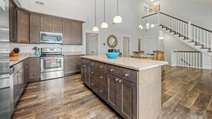 A spacious kitchen with dark wooden cabinets, stainless steel appliances, and a large island. - 4BR All Ensuite Baths + Bonus Living Area + Hot Tub + Pet-Friendly + Corolla Lt (Corolla)