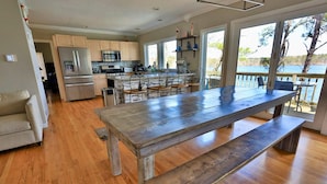 A modern kitchen with a large island, wooden flooring, and a view of a lake.