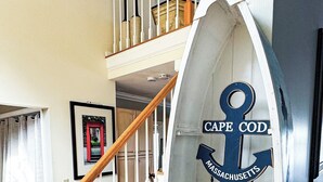 A staircase with a wooden handrail and white balusters, leading to a landing with a sign reading "CAPE COD MASSACHUSETTS".