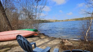 A lakeside setting with chairs and canoes.