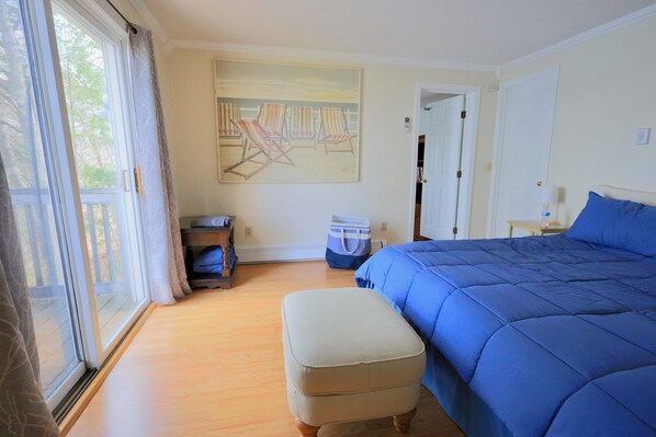 Un dormitorio con una cama grande, una ventana con cortinas, un cuadro en la pared y suelo de madera.