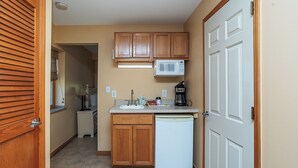 A compact kitchen with wooden cabinets, a microwave, a coffee maker, and a dishwasher.