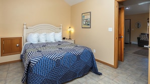 A bedroom with a bed, a nightstand, a lamp, a door, and a poster on the wall.
