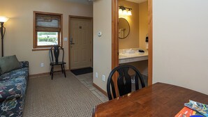 A compact room with a wooden dining table, two chairs, a sofa, and a small window. - A Suite Place .5 mi from Beach (Michigan City)