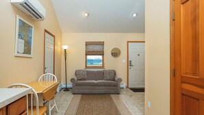 A compact living space with a dining area, a sofa, and a view of the outdoors.