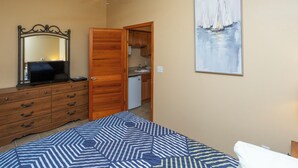 A bedroom with a bed, dresser, mirror, ceiling fan, and a painting of sailboats. - A Suite Place .5 mi from Beach (Michigan City)