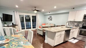 A modern kitchen with white cabinets, a built-in oven, and a dining area with a colorful table and chairs. - Carolina Beach Ocean View Retreat w/ Beach Access! (Carolina Beach)