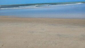 Una playa con cielo despejado y mar tranquilo.