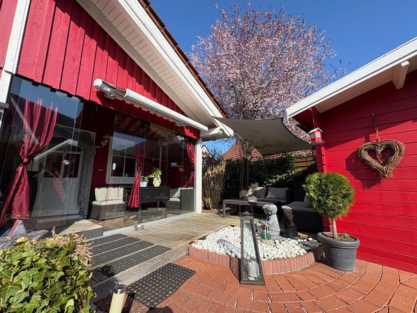 A red building with a covered patio area, outdoor seating, and a heart-shaped decoration on the wall. - Pet-friendly Swedish red house! (Haselünne)