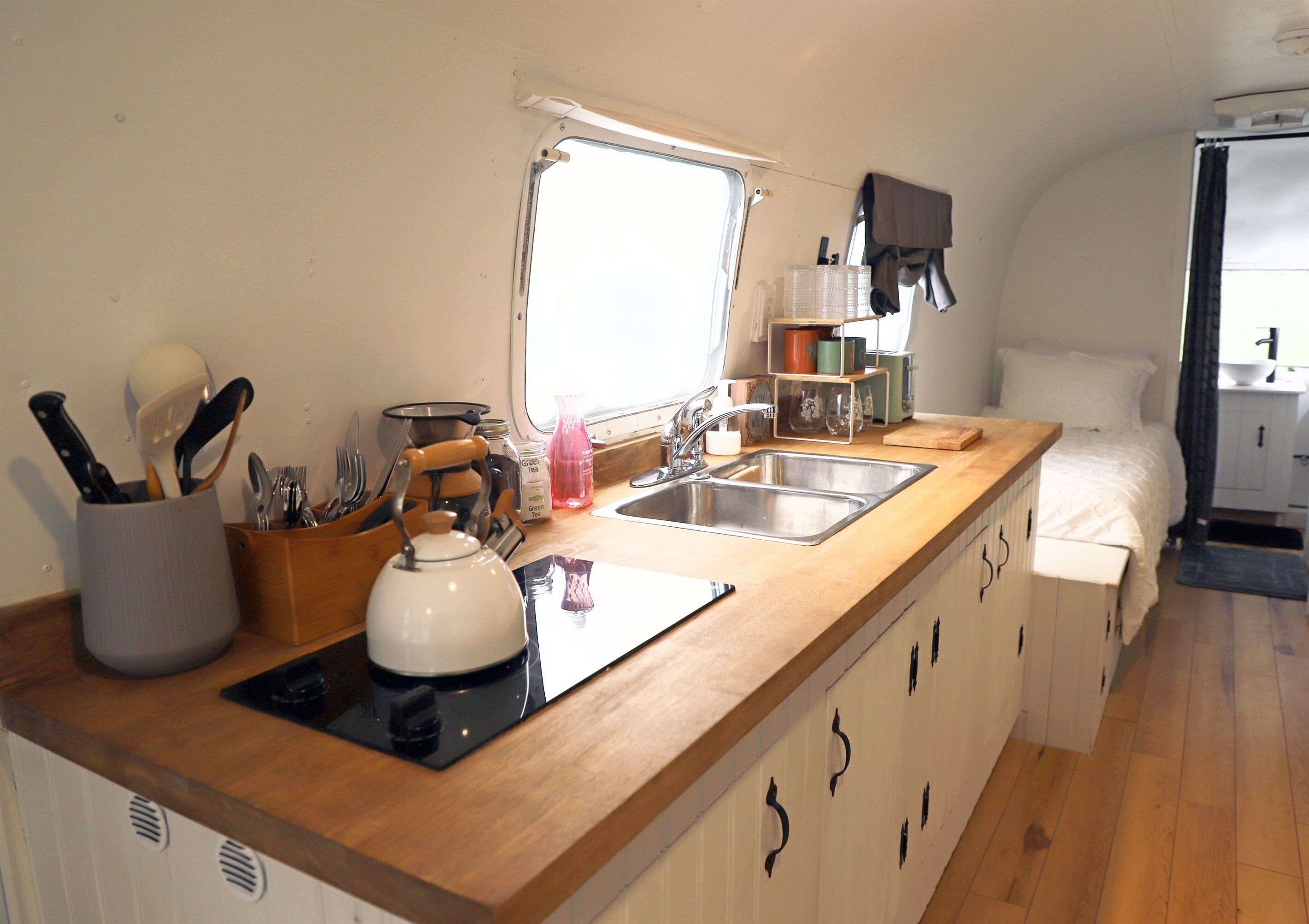 A compact kitchen with a sink, stove, and wooden countertop.