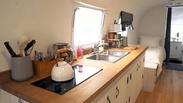A compact kitchen with a sink, stove, and wooden countertop.