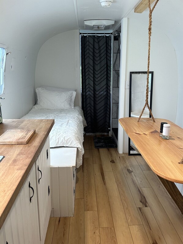 Una habitación pequeña con cama, una mesita y una hamaca colgante.