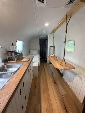 Una cocina compacta con cubierta de madera, un lavamanos y un pequeño comedor con un columpio colgante.