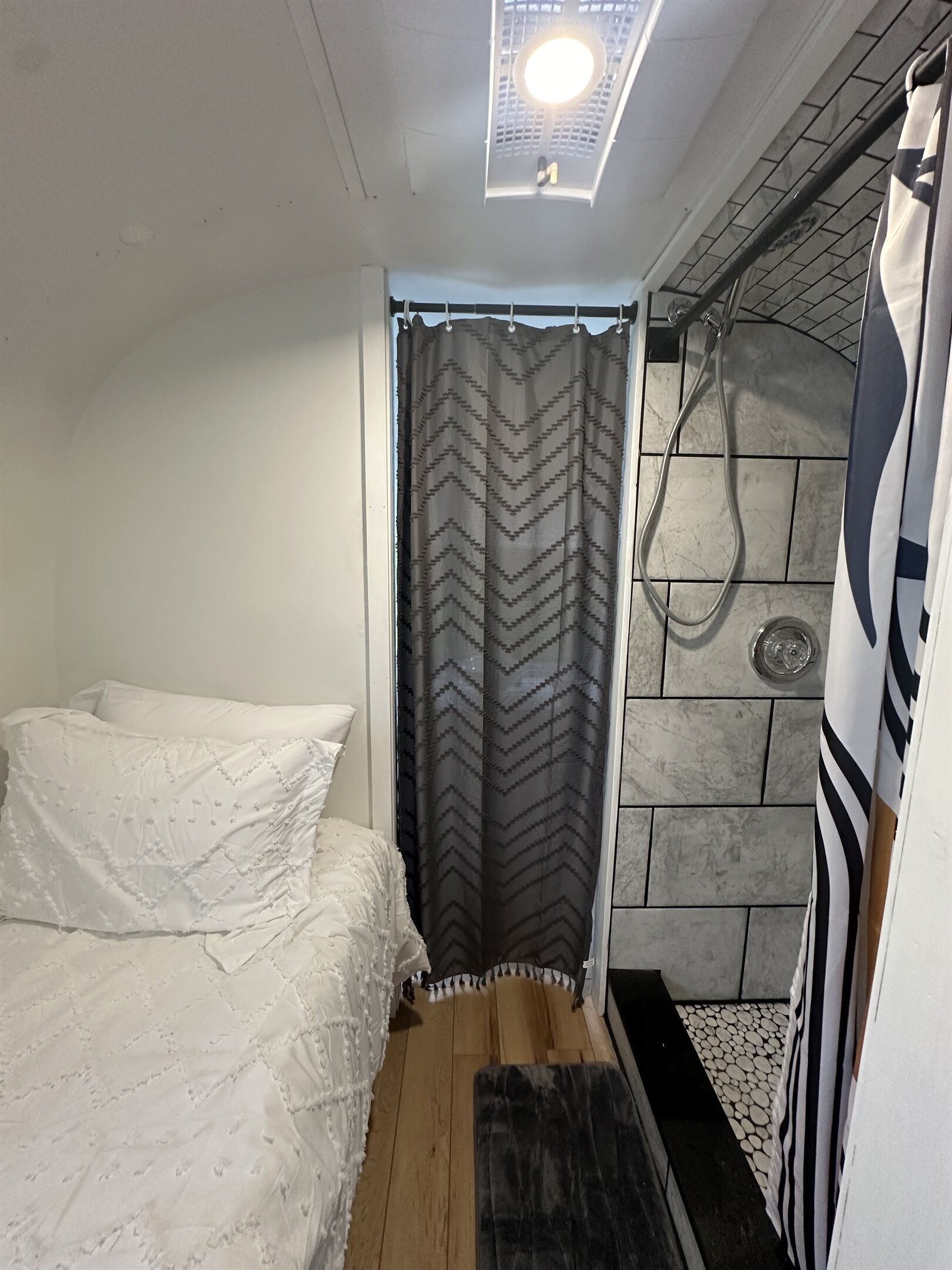 Una habitación pequeña y funcional con cama, ducha y tragaluz.