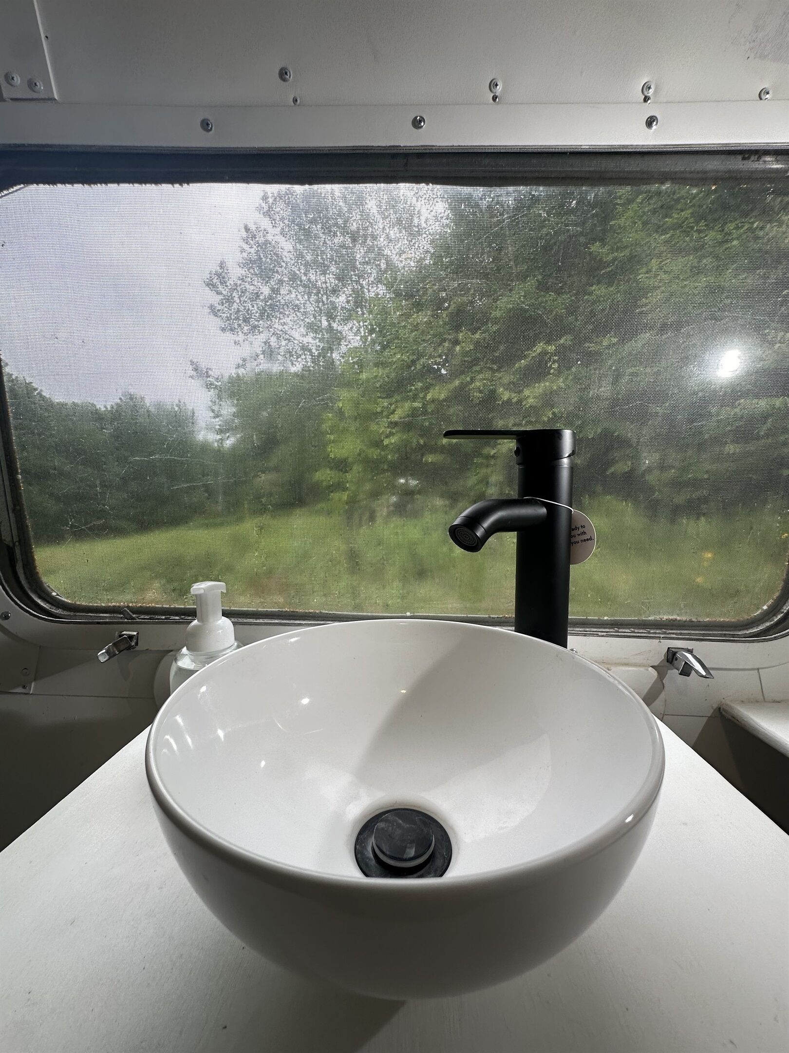 A white sink with a black faucet in a train compartment.