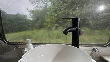 A white sink with a black faucet in a train compartment.