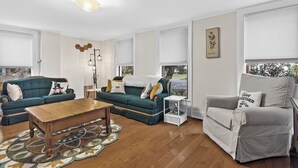 A living room with a wooden coffee table, two green sofas, a grey armchair, and a patterned rug. - *NEW*Hops House-Sleeps10-8Mi.toCDP&15Mi.toASV (Hartwick)