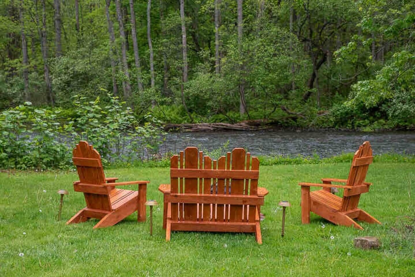 Zwei Adirondack-Stühle mit Blick auf einen See, im Hintergrund ein Wald.