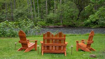 Zwei Adirondack-Stühle mit Blick auf einen See, im Hintergrund ein Wald.