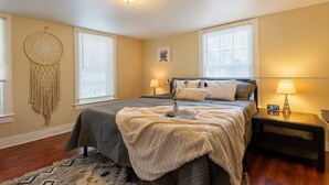 Een slaapkamer met een bed, bedlampjes, een dromenvanger en een klok op het nachtkastje.
