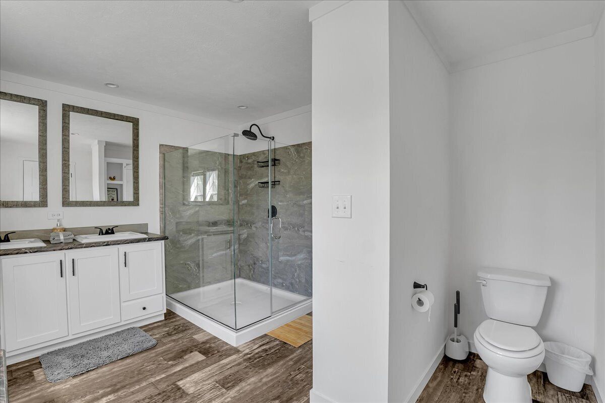 A modern bathroom with a glass-enclosed shower, white cabinetry, and a marble backsplash.
