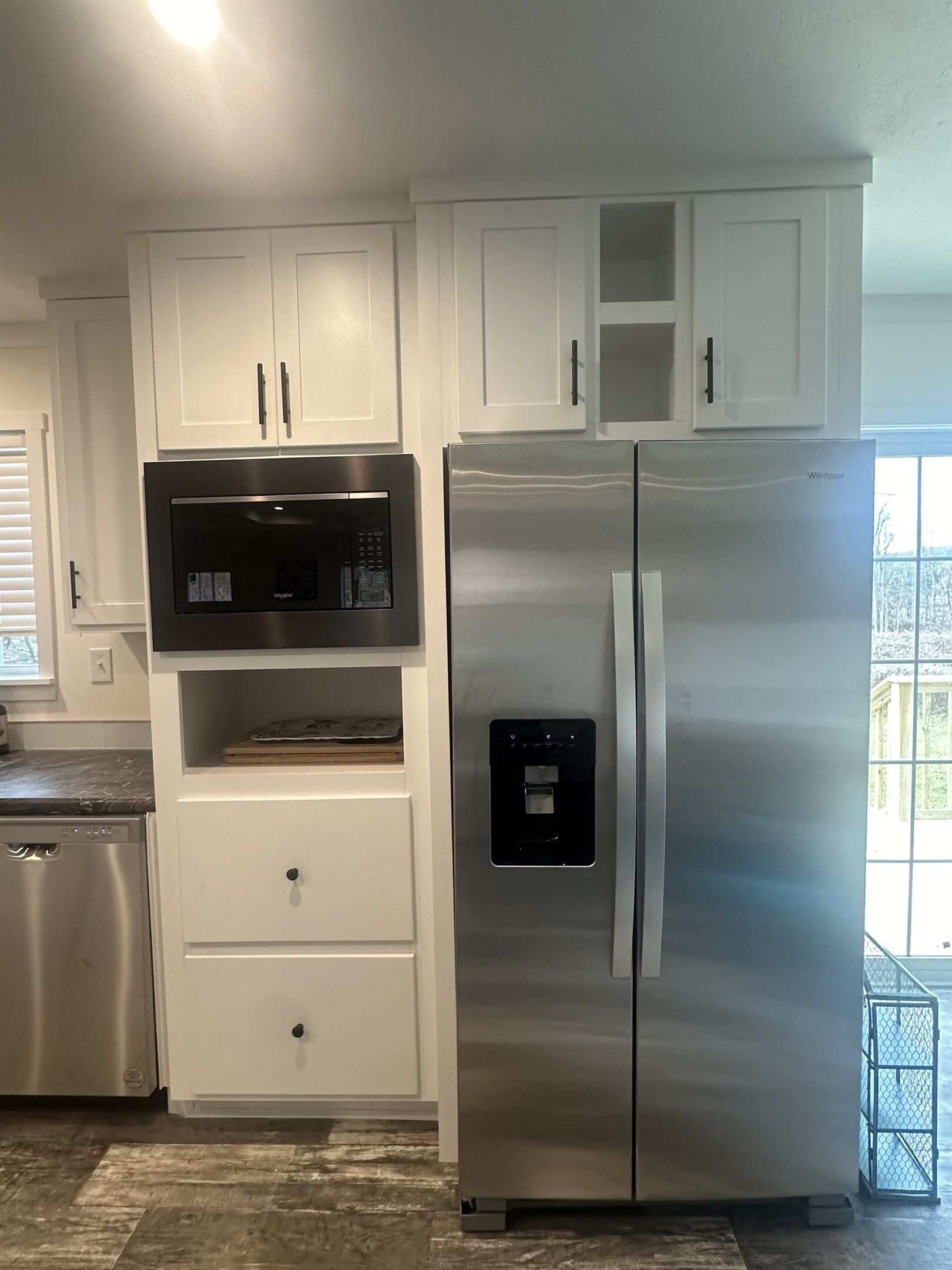 Una cocina con armarios blancos, un refrigerador de acero inoxidable, un microondas y un lavavajillas.