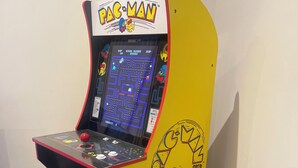 Una máquina recreativa de Pac-Man con diseño amarillo y negro, que presenta el logo y los personajes del juego.