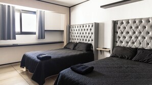 Ein Hotelzimmer mit zwei Betten, einem Fenster mit Vorhängen, einem modernen Kopfteil und einem Nachttisch.