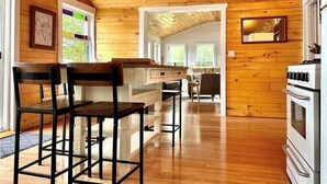 A wooden interior with a kitchen area, bar stools, and a dining table. - Come play in the water at this secluded get away.
Observe nature at its best.
 (Little Ridge)