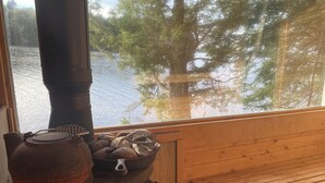 A rustic cabin with a wood-burning stove, a wooden table, and a view of a lake with trees. - Come play in the water at this secluded get away.
Observe nature at its best.
 (Little Ridge)