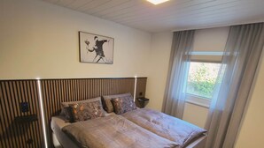 A bedroom with a bed, a ceiling light, a window with curtains, and a wall-mounted artwork. - Your getaway! Cozy - Nature - Panoramic views! (Lichtenau)