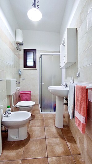 A bathroom with a toilet, bidet, sink, and shower.