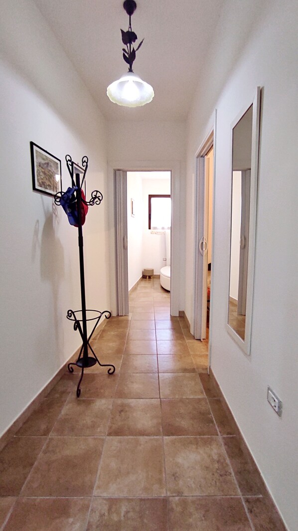 Un pasillo con una lámpara de pie, un perchero y un espejo en la pared.
