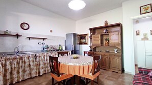 Uma cozinha compacta com mesa de jantar, cadeiras, geladeira e pia.