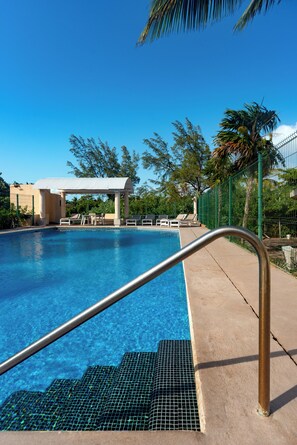 A swimming pool with a metal handrail, lounge chairs, and a covered pavilion. - Villa in Laguna, Cancun   (Cancún)